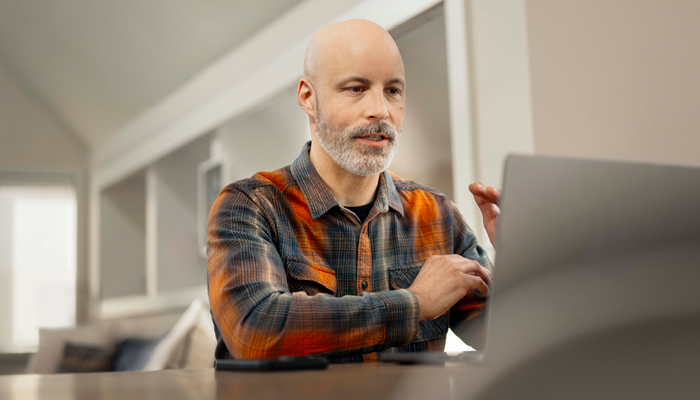 man in a orange and grey flannel using his laptop